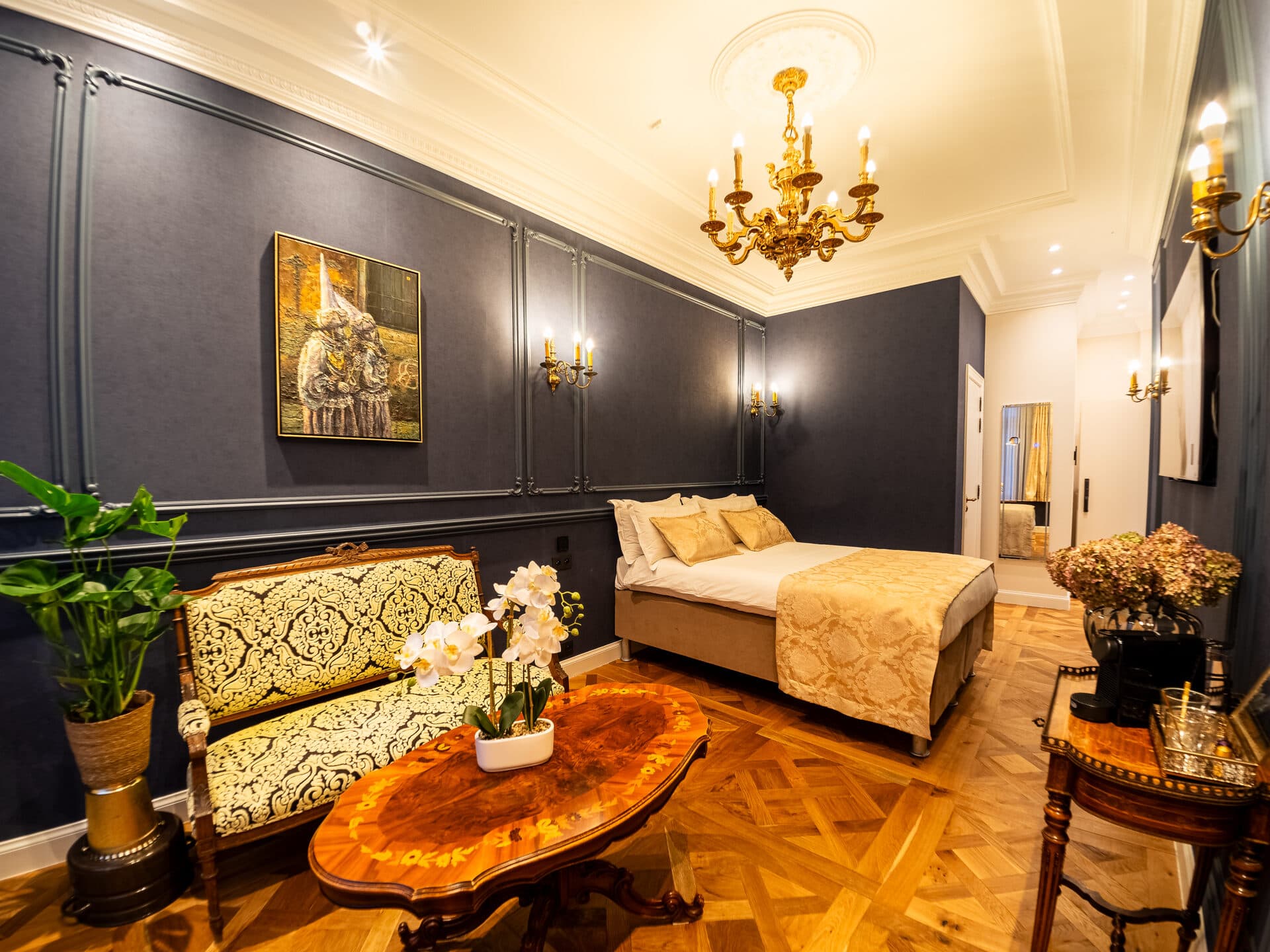 Deluxe Double Room with navy walls, antique loveseat, and ornate chandelier